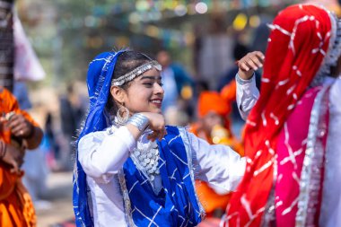 Faridabad, Haryana, Hindistan - 4 Şubat 2023: Surajkund fuarı sırasında Haryana 'nın etnik elbise ve mücevherleriyle dans eden güzel kızlar.