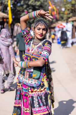 Faridabad, Haryana, Hindistan - Şubat 04 2023: Surajkund sanat fuarında geleneksel elbiseler içinde dans eden bir kadın sanatçının portresi.