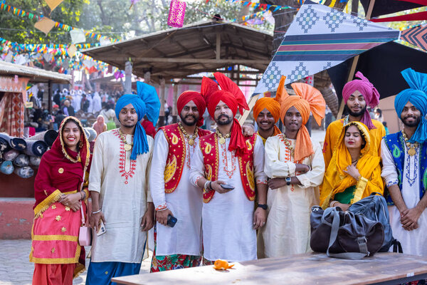 Faridabad, Haryana, India - February 04 2023: Group of male and female sikh people in traditional punjabi clothes and turban during a bhangra dance performance at surajkund craft fair