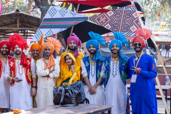 Faridabad, Haryana, India - February 04 2023: Group of male and female sikh people in traditional punjabi clothes and turban during a bhangra dance performance at surajkund craft fair
