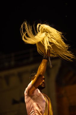 Varanasi, Uttar Pradesh, Hindistan - 3 Mart 2023: Ganga aarti, Dashashwamedh ghat geleneksel elbise ve Hindu ayinleri ile kutsal nehir ganges akşam aarti performans genç rahip portresi