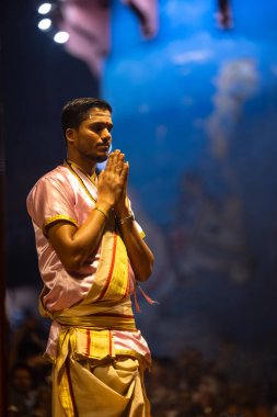 Varanasi, Uttar Pradesh, Hindistan - 3 Mart 2023: Ganga aarti, Dashashwamedh ghat geleneksel elbise ve Hindu ayinleri ile kutsal nehir ganges akşam aarti performans genç rahip portresi