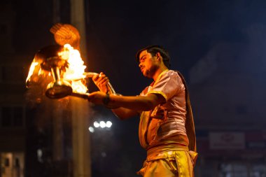 Varanasi, Uttar Pradesh, Hindistan - 3 Mart 2023: Ganga aarti, Dashashwamedh ghat geleneksel elbise ve Hindu ayinleri ile kutsal nehir ganges akşam aarti performans genç rahip portresi