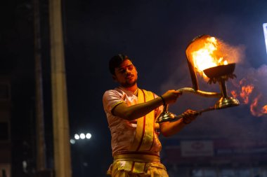 Varanasi, Uttar Pradesh, Hindistan - 3 Mart 2023: Ganga aarti, Dashashwamedh ghat geleneksel elbise ve Hindu ayinleri ile kutsal nehir ganges akşam aarti performans genç rahip portresi