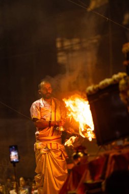 Varanasi, Uttar Pradesh, Hindistan - 3 Mart 2023: Ganga aarti, Dashashwamedh ghat geleneksel elbise ve Hindu ayinleri ile kutsal nehir ganges akşam aarti performans genç rahip portresi