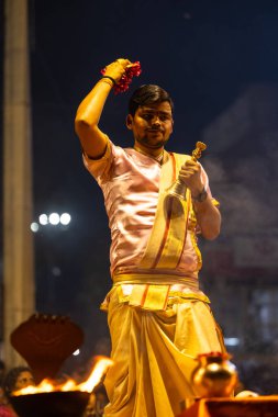 Varanasi, Uttar Pradesh, Hindistan - 3 Mart 2023: Ganga aarti, Dashashwamedh ghat geleneksel elbise ve Hindu ayinleri ile kutsal nehir ganges akşam aarti performans genç rahip portresi