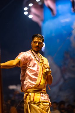 Varanasi, Uttar Pradesh, Hindistan - 3 Mart 2023: Ganga aarti, Dashashwamedh ghat geleneksel elbise ve Hindu ayinleri ile kutsal nehir ganges akşam aarti performans genç rahip portresi