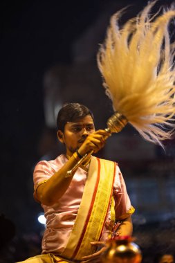 Varanasi, Uttar Pradesh, Hindistan - 3 Mart 2023: Ganga aarti, Dashashwamedh ghat geleneksel elbise ve Hindu ayinleri ile kutsal nehir ganges akşam aarti performans genç rahip portresi