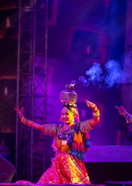 Puşkar, Rajasthan, Hindistan - Kasım 05 2022: Pushkar Fuarı 'nda geleneksel renkli elbise ve metal tencereyle rajasthani halk dansı yapan kadın sanatçı. Seçici odak