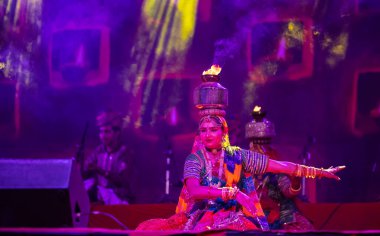 Puşkar, Rajasthan, Hindistan - Kasım 05 2022: Pushkar Fuarı 'nda geleneksel renkli elbise ve metal tencereyle rajasthani halk dansı yapan kadın sanatçı. Seçici odak