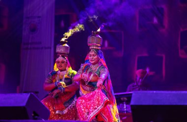 Pushkar, Rajasthan, India - November 05 2022: Female artists performing rajasthani folk dance Ghoomar in traditional colorful dresses and metal pots with fire on heads in Pushkar fair. Selective focus clipart