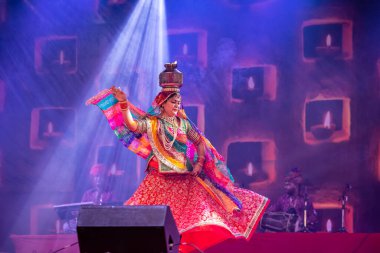 Puşkar, Rajasthan, Hindistan - Kasım 05 2022: Pushkar Fuarı 'nda geleneksel renkli elbise ve metal tencereyle rajasthani halk dansı yapan kadın sanatçı. Seçici odak