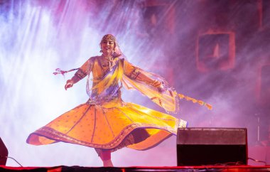 Puşkar, Rajasthan, Hindistan - 05 Kasım 2022: Renkli bir etnik rajasthani elbisesi içinde pulkar fuarında dans eden genç ve güzel kadın sanatçının portresi. Sanatçıya Seçici Odaklanma