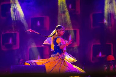 Puşkar, Rajasthan, Hindistan - 05 Kasım 2022: Renkli bir etnik rajasthani elbisesi içinde pulkar fuarında dans eden genç ve güzel kadın sanatçının portresi. Sanatçıya Seçici Odaklanma