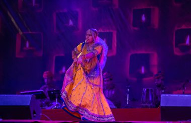 Puşkar, Rajasthan, Hindistan - 05 Kasım 2022: Renkli bir etnik rajasthani elbisesi içinde pulkar fuarında dans eden genç ve güzel kadın sanatçının portresi. Sanatçıya Seçici Odaklanma