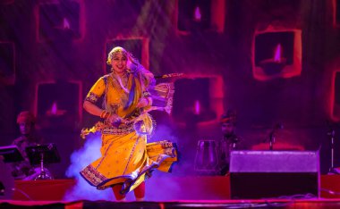 Puşkar, Rajasthan, Hindistan - 05 Kasım 2022: Renkli bir etnik rajasthani elbisesi içinde pulkar fuarında dans eden genç ve güzel kadın sanatçının portresi. Sanatçıya Seçici Odaklanma