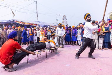 Anandpur Sahib, Punjab, Hindistan - 19 Mart 2022: Holi festivali sırasında Hola Mohalla 'nın Anandpur Sahib' te kutlaması sırasında Sikh erkek (Nihang Sardar) portresi dövüş sanatlarını kültür olarak icra ediyor