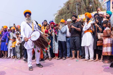 Anandpur Sahib, Punjab, Hindistan - 19 Mart 2022: Holi festivali sırasında Hola mohalla kutlaması sırasında bhangra dhol veya davul çalan yaşlı Sikh erkek portresi.
