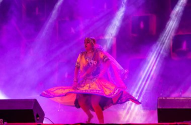 Puşkar, Rajasthan, Hindistan - 05 Kasım 2022: Renkli bir etnik rajasthani elbisesi içinde pulkar fuarında dans eden genç ve güzel kadın sanatçının portresi. Sanatçıya Seçici Odaklanma