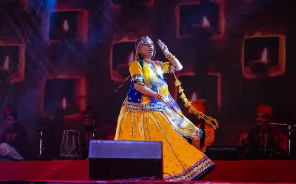 stock image Pushkar, Rajasthan, India - November 05, 2022: Portrait of young beautiful female artist performing dance during pushkar fair in colorful ethnic rajasthani dress. Selective focus on artist