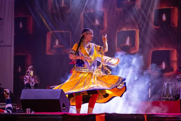 stock image Pushkar, Rajasthan, India - November 05, 2022: Portrait of young beautiful female artist performing dance during pushkar fair in colorful ethnic rajasthani dress. Selective focus on artist