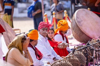 Puşkar, Rajasthan, Hindistan - Kasım 06, 2022: Tanımlanamayan turistler fuar sırasında fuar alanında renkli kıyafetler içinde davul çalıyorlar