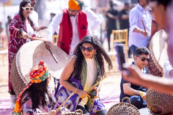 stock image Pushkar, Rajasthan, India - November 06, 2022: Unidentified tourists playing drums in colorful clothes at fair ground during the pushkar camel fair