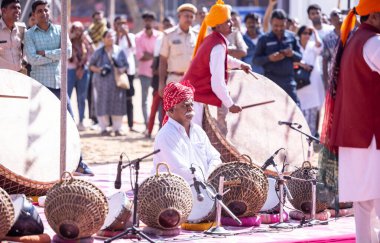 Puşkar, Rajasthan, Hindistan - Kasım 06, 2022: Tanımlanamayan turistler itme deve fuarı sırasında renkli giysiler içinde davul çalıyorlar