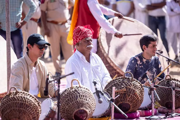 Puşkar, Rajasthan, Hindistan - Kasım 06, 2022: Tanımlanamayan turistler itme deve fuarı sırasında renkli giysiler içinde davul çalıyorlar