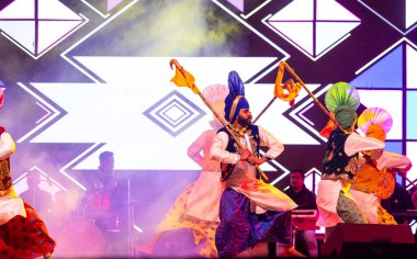 Bikaner, Rajasthan, India - January 14, 2023: Group of punjabi artists from punjab performing bhangra dance in traditional colourful clothes at bikaner camel festival clipart