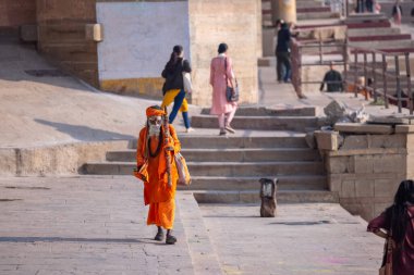 Varanasi, Uttar Pradesh, Hindistan - 05 Mart 2023: Varanasi 'deki çetelerin yakınındaki ghatlarda yürüyen geleneksel sadhu baba resmi