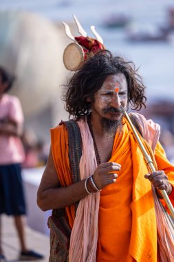 Varanasi, Uttar Pradesh, Hindistan - 05 Mart 2023: Varanasi 'deki çetelerin yakınındaki ghatlarda yürüyen geleneksel sadhu baba resmi