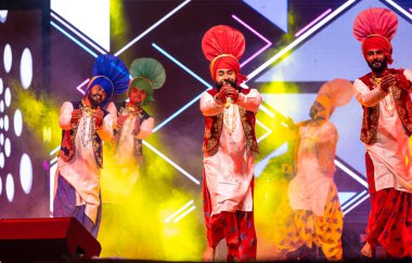 Bikaner, Rajasthan, India - January 14 2023: Group of young punjabi male artists from punjab performing famous bhangra dance in traditional colourful  at bikaner camel festival clipart