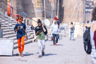 Varanasi, Uttar Pradesh, Hindistan - Mart 05 2023: Kaşhi 'deki kutsal nehir çetelerinin yakınlarındaki ghat üzerinde yürüyen erkek Forin turistlerin portresi. Dünyanın dört bir yanındaki turistler Varanasi 'yi Hindu tanrısı Shiv' e ibadet etmek için ziyaret ederler..