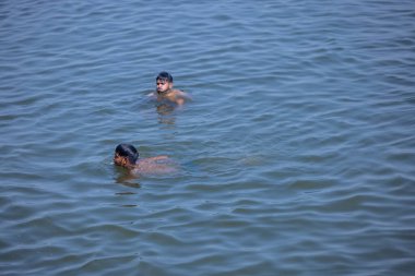 Varanasi, Uttar Pradesh, Hindistan - 05 Mart 2023: Nehir çetelerinde yüzen gençlerin portresi.