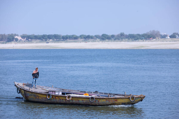 Varanasi, Uttar Pradesh, India - March 05 2023: Tourists enjoying boat ride in the river ganges at varanasi during early morning. Boatman sailing the wooden boat.