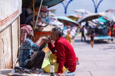 Varanasi, Uttar Pradesh, Hindistan - Mart 05 2023: İş yerinde tanışma, sokak berberi Varanasi 'deki Hindu ayinlerinin bir parçası olarak çetelerin yanında saç ve sakal traşı oldu.