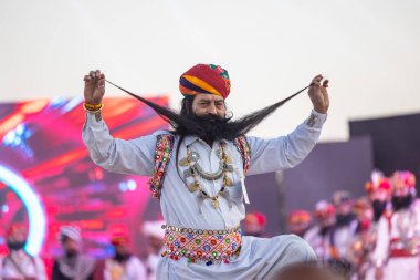 Bikaner, Rajasthan, Hindistan - 14 Ocak 2023: Bikaner deve festivalinde geleneksel Rajasthani elbisesi, mücevheri ve türban giyen sakallı ve bıyıklı bir rajasthani erkeğinin portresi.