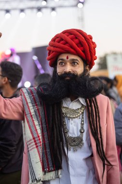 Bikaner, Rajasthan, Hindistan - 14 Ocak 2023: Bikaner deve festivalinde geleneksel Rajasthani elbisesi, mücevheri ve türban giyen sakallı ve bıyıklı bir rajasthani erkeğinin portresi.