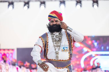 Bikaner, Rajasthan, Hindistan - 14 Ocak 2023: Bikaner deve festivalinde geleneksel Rajasthani elbisesi, mücevheri ve türban giyen sakallı ve bıyıklı bir rajasthani erkeğinin portresi.
