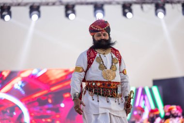 Bikaner, Rajasthan, Hindistan - 14 Ocak 2023: Bikaner deve festivalinde geleneksel Rajasthani elbisesi, mücevheri ve türban giyen sakallı ve bıyıklı bir rajasthani erkeğinin portresi.