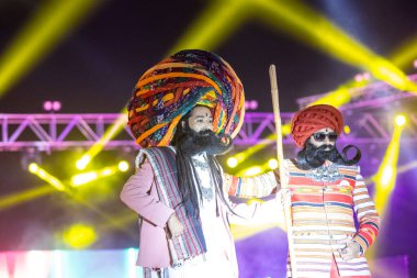 Bikaner, Rajasthan, Hindistan - 14 Ocak 2023: Bikaner deve festivalinde geleneksel Rajasthani elbisesi, mücevheri ve türban giyen sakallı ve bıyıklı bir rajasthani erkeğinin portresi.