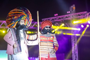 Bikaner, Rajasthan, Hindistan - 14 Ocak 2023: Bikaner deve festivalinde geleneksel Rajasthani elbisesi, mücevheri ve türban giyen sakallı ve bıyıklı bir rajasthani erkeğinin portresi.