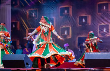 Puşkar, Rajasthan, Hindistan - Kasım 05 2022: Renkli etnik Rajasthani elbisesi içindeki itme kar fuarı sırasında genç ve güzel kadın sanatçının başıyla halk dansını sergileyen portresi.