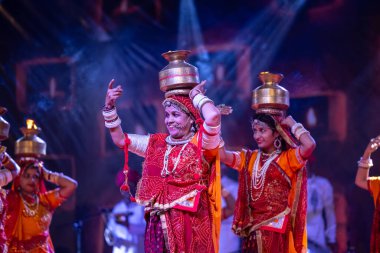 Puşkar, Rajasthan, Hindistan - 05 Kasım 2022: Pushkar Fuarı 'nda geleneksel renkli elbiseler ve ateşli metal kaplarla rajasthani halk dansı yapan kadın sanatçılar. Seçici odak.