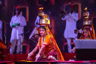 Pushkar, Rajasthan, India - November 05, 2022: An female artists performing rajasthani folk dance Ghoomar in traditional colorful dresses and metal pots with fire in Pushkar fair. Selective focus. clipart