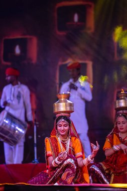 Puşkar, Rajasthan, Hindistan - 05 Kasım 2022: Pushkar Fuarı 'nda geleneksel renkli elbiseler ve ateşli metal kaplarla rajasthani halk dansı yapan kadın sanatçılar. Seçici odak.