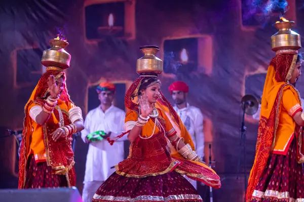 Puşkar, Rajasthan, Hindistan - 05 Kasım 2022: Pushkar Fuarı 'nda geleneksel renkli elbiseler ve ateşli metal kaplarla rajasthani halk dansı yapan kadın sanatçılar. Seçici odak.