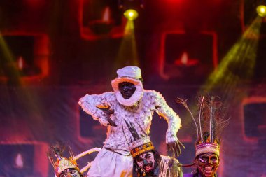 Puşkar, Rajasthan, Hindistan - Kasım 06 2022: Hintli erkek sanatçı rajasthani folk dansı yapıyor Sahariya kabilesi boyalı yüzlü ve renkli boyalı vücutlu, açık renk elbiseli.