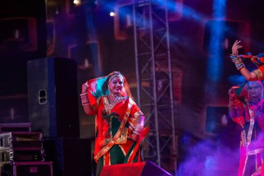 Puşkar, Rajasthan, Hindistan - Kasım 05 2022: Renkli etnik Rajasthani elbisesi içindeki itme kar fuarı sırasında genç ve güzel kadın sanatçının başıyla halk dansını sergileyen portresi.